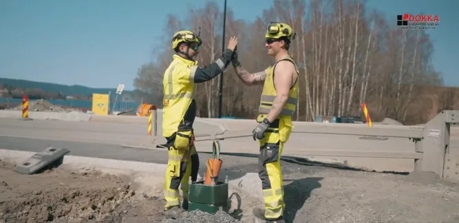 To ansatte i Dokka Entreprenør gir hverandre high five på anlegget